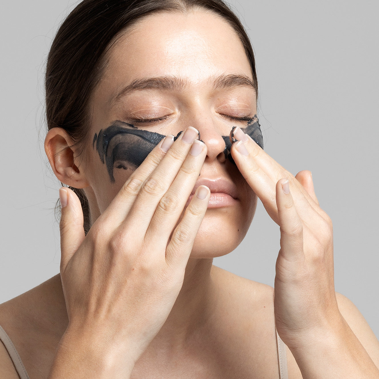 Frau entfernt mit den Fingern eine schwarze Gesichtsmaske von Nase und Wangen.