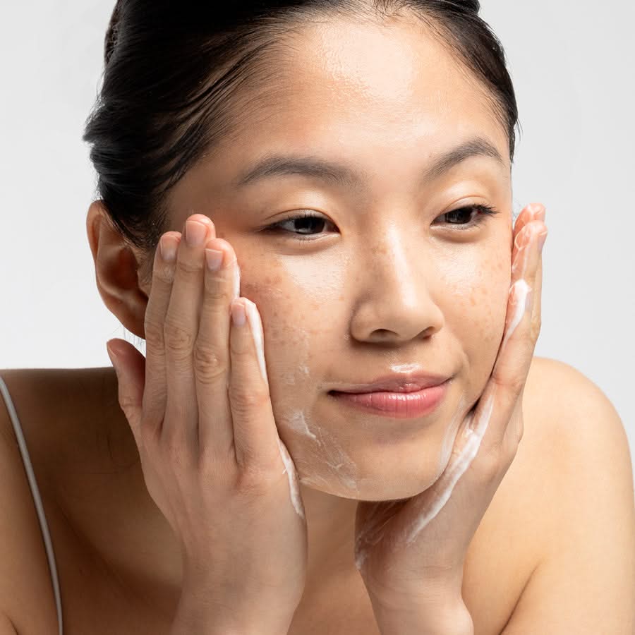 Frau wäscht ihr Gesicht, während sie sanft ihre Wangen massiert.