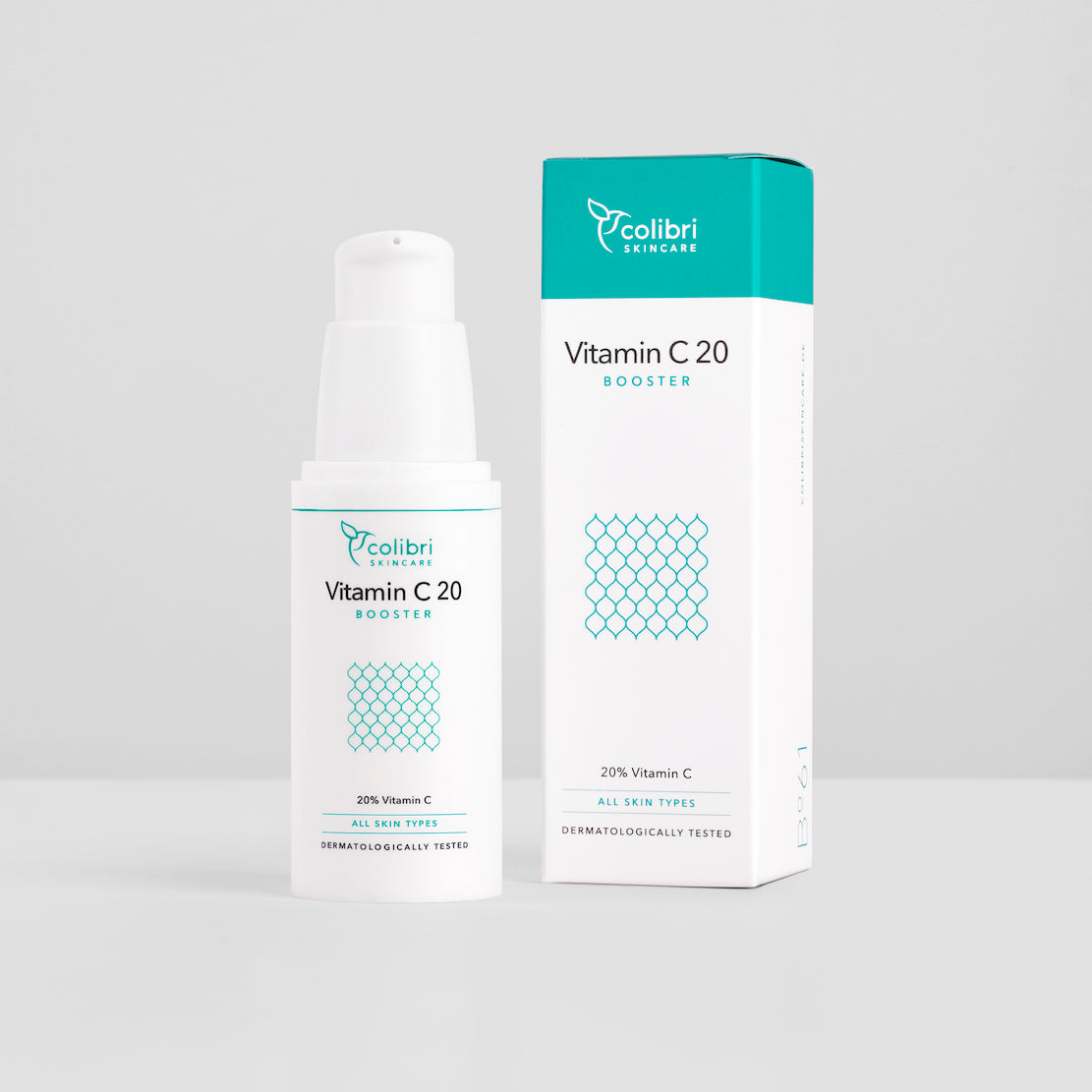 Flasche und Verpackung eines Vitamin C 20 Boosters von Colibri Skincare vor grauem Hintergrund.