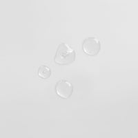 Vier Wassertropfen auf einer glatten, weißen Oberfläche.